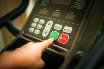 Start running - Hand pressing start on treadmill.