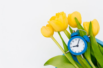 Womans holiday yellow Spring tulips with an alarm clock and blue wooden cart box isolated on white...