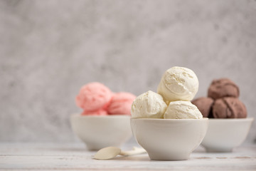 Bowl of vanilla, chocolate and pink berries ice cream on light background. Side view