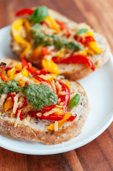 Red and yellow bell pepper, vegan cheese and home made vegan basil pesto on toasted slices of bread.