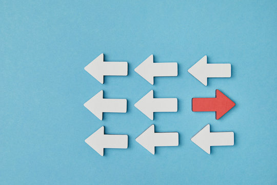 top view of red pointer opposite white arrows in rows on blue background