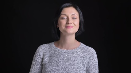 Closeup portrait of beautiful adult caucasian female with black short hair looking straight at camera and smiling happily