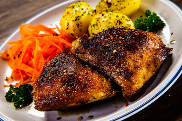Grilled thighs with boiled potatoes and vegetable salad on wooden table