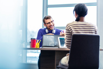 Joyful young man having pleasant talk with colleague