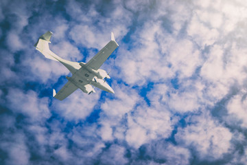 Fototapeta na wymiar a small private white plane with screws flies on the background blue sky with clouds