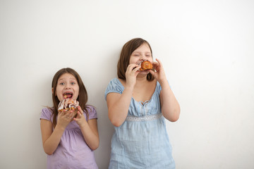 Funny hungry girls eat sweet buns on light