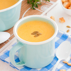 Pumpkin soup in a blue enameled mug, selective focus