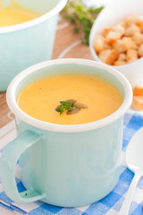 Pumpkin soup in a blue enameled mug, selective focus