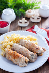 Small pork rolls with champignons on a white plate with pasta and ketchup, selective focus