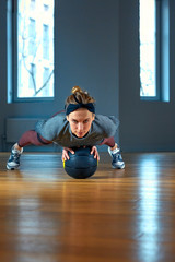 beautiful fit woman in sportswear posing while sitting on the floor with basketball in front of window at gym Healthy girl lifestyle and sport concept