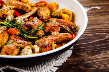 Roast chicken wings with vegetables served on frying pan