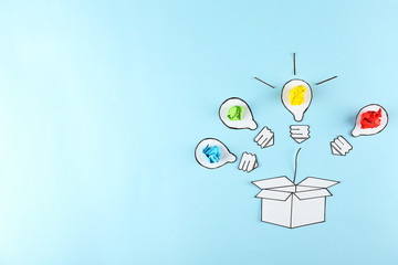Thinking outside the box concept. Drawn paper lightbulb as a metaphor for fresh idea on blue gradient background. Close up, copy space, top view, flat lay.