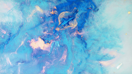 Colorful sparkling paints mix in beautiful patterns. Oil ink of blue, white, turquoise, purple and other colors spread on the surface and mix one into another creating amazing textures and design.