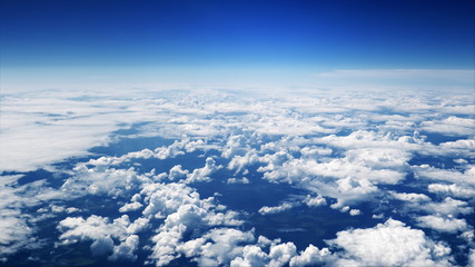 Flying over picturesque white clouds on the deep blue sky. Beautiful moving clouds view from airplane window. Traveling through clear blue cloudscape.