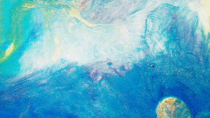 Colorful sparkling paints mix in beautiful patterns. Oil ink of blue and other colors spread on the surface and mix one into another creating amazing textures and design.