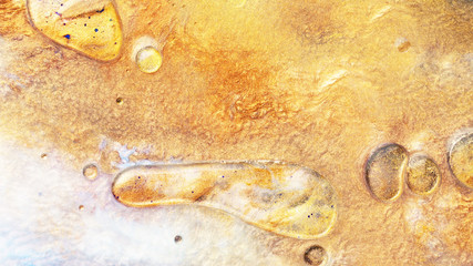 Colorful sparkling paints mix in beautiful patterns. Oil ink of yellow and other colors spread on the surface and mix one into another creating amazing textures and design.