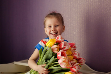 Cute little girl holding a bouquet of tulips. Portrait. Girl with tulips. Mother's Day, March 8, International Women's Day