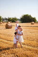 Naklejka na ściany i meble happy family, mom, dad, son and daughter in the field against the haystack, in the morning, in white clothes