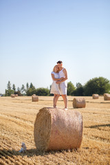 Naklejka na ściany i meble happy and happy young couple in love standing on the hay, cuddling 