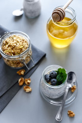 Chia seed pudding with granola, blueberry, walnut and honey decorated mint leaves on gray backgraund. Selective focus. Healthy eating or vegetarian food concept