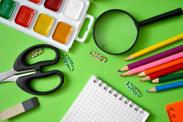 school subjects: pens, notebooks, pencils, paper clips on a light green background