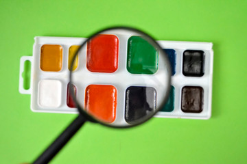 watercolor paint and magnifying glass on green background