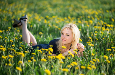 Image of pretty woman lying down on dandelions field, happy cheerful girl resting on dandelions meadow, relaxation outdoor in springtime, vacation 