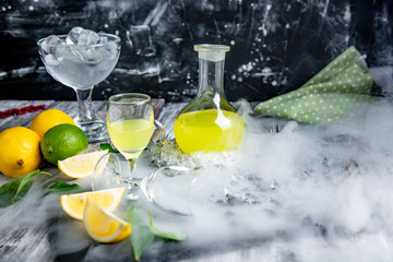Italian typical digestive limoncello with fresh lemons in smoke, selective focus
