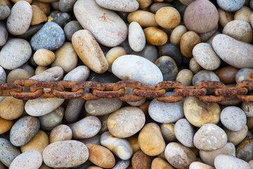Rusty chain laid on pebbles, Chesil beach, Weymouth, Dorset.