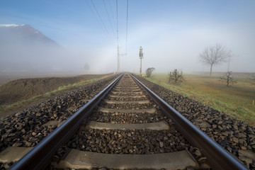 Fototapeta premium Railroad Tracks in the Fog and Mountain in Switzerland.