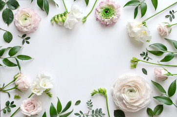 Fototapeta na wymiar Frame of various delicate flowers and leaves on a white background with space for text. Beautiful floral background. Top view. Copy space. Mock-up