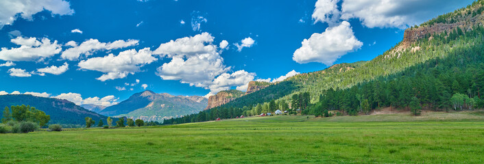 Panoramic View of Alpine Meadow with Farm.