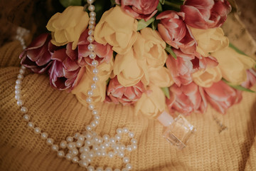 Pink and yellow tulips bouquet lying on a yellow knitted fabric