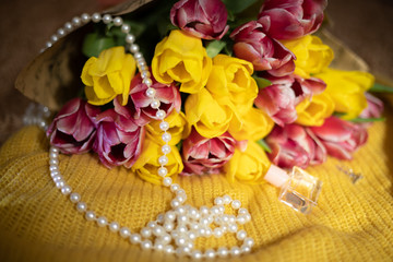 Pink and yellow tulips bouquet lying on a yellow knitted fabric