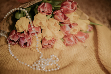 Pink and yellow tulips bouquet lying on a yellow knitted fabric