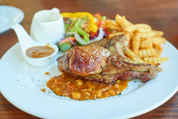 Pork Chop Steak Served with salad vegetables and French fries, topped with delicious BBQ sauce