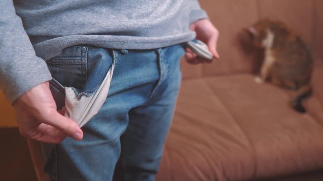 man and cat shows turns empty pockets bankrupt no money. poverty Finance business bankruptcy concept. a man in old jeans looking for money in his pockets. crisis of getting into debt lifestyle