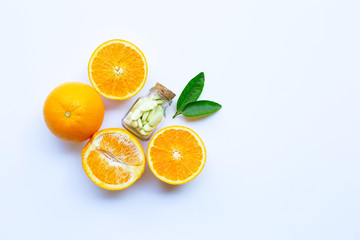 Vitamin C bottle and pills with orange fruit on white
