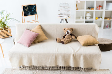 cosy living room with pillows and teddy bear assembled on comfortable sofa