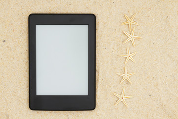 An e-reader on the beach for your summer reading with five starfish