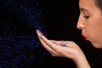 ragazza soffia brillantini azzurri su fondo nero
