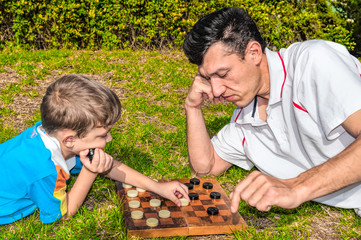 Father and son playing checkers on the grass