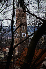 Clock tower in old city through bare trees View of old brick clock tower in city through leafless trees in cold season