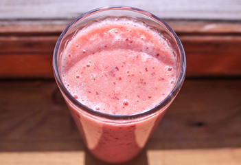 Pink smoothies in the glass on the wooden background