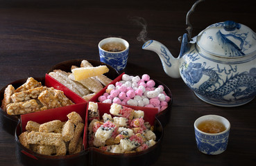 Chinese snack and Chinese tea on old brown wooden table in dim light