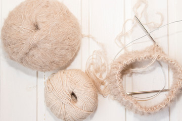 Beige yarn balls on the white background, needles.  Future cap