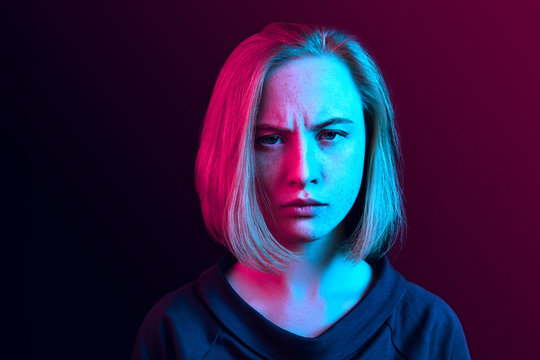 Why is that. Beautiful female half-length portrait isolated on trendy neon studio backgroud. Young emotional surprised, frustrated and bewildered woman. Human emotions, facial expression concept.