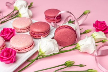 Pink macarons with pearls and white roses for womens day on a cleare pink background with blank space for design elements and text