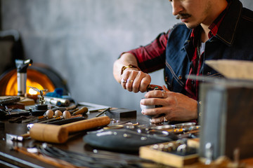 young ambitious craftsman fixing a jewel in the earring. close up cropped photo, handcraft