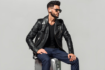 Elegant young handsome man with luggage. Studio fashion portrait.